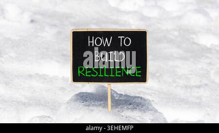 So erstellen Sie ein Resilienzsymbol. Konzeptworte wie man Widerstandsfähigkeit auf schönen Tafeln schafft. Schöner weißer Schnee Hintergrund. Business wie man baut Stockfoto