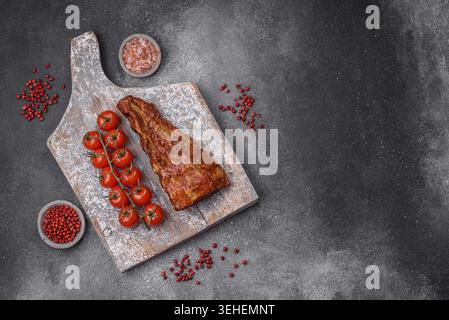 Essen, köstliche gegrillte oder geräucherte Schweinerippchen mit Salz, Gewürzen und Kräutern auf strukturiertem Betonhintergrund Stockfoto