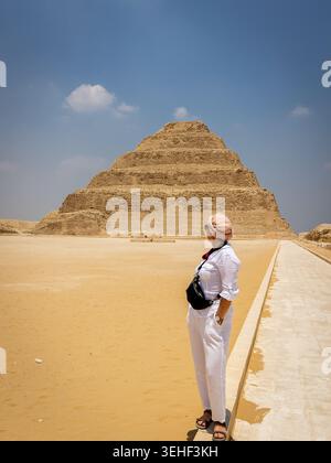 Die Pyramide von Djoser (Stufenpyramide von Djoser, Stufenpyramide von Horus Neterikhet) in Sakkara Nekropolis, Ägypten mit weiblichen Touristen davor. Stockfoto