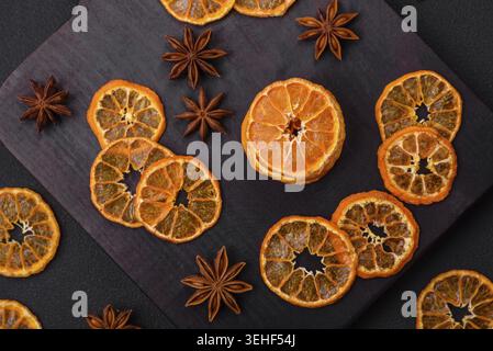 Essen, Getrocknete runde Scheiben von helloranger Mandarine auf einem dunklen texturalen Hintergrund Stockfoto