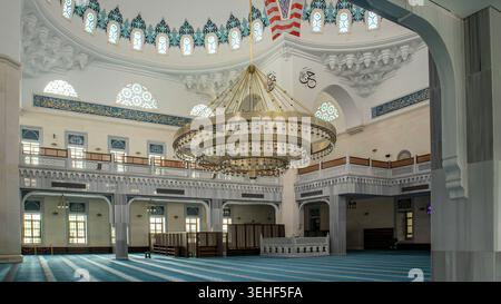 ISTANBUL, Türkiye - 30. April 2026. Basaksehir Millet Camii. Die Weitwinkelansicht zeigt eine große Moschee mit einem massiven goldenen Kronleuchter. Stockfoto