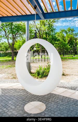 Ovale weiße Plastikschaukel im Erholungsbereich Stockfoto