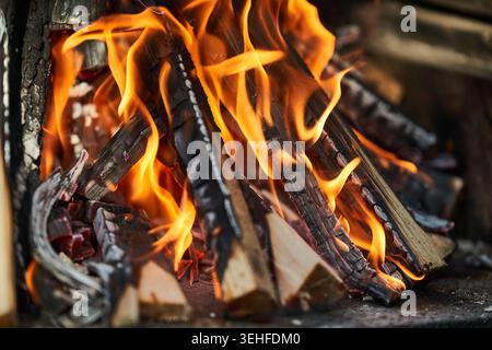 Nahaufnahme von brennendem Holz mit leuchtenden orangen Flammen, glühender Glut und gemütlichem warmen Feuerstein in Baumstämmen. Stockfoto