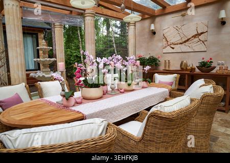 Eleganter Orchideentisch im luxuriösen Glaskonservatorium Stockfoto