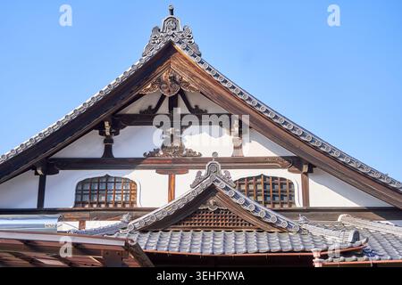 Nahaufnahme der traditionellen japanischen Tempelarchitektur mit kunstvoller hölzerner Giebelkonstruktion, aufwendigen Schnitzereien und dunklen Holzbalken. Stockfoto