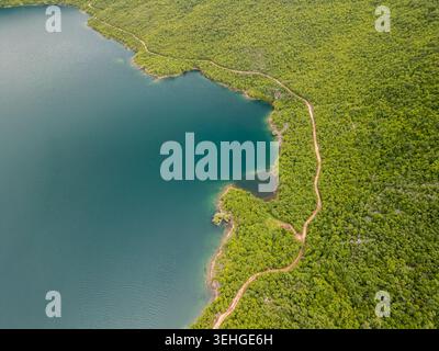 Slansko Lake, Montenegro - 05 29 2025: Abgewinkeltes Drohnenfoto, das einen üppig grünen, bewaldeten Hügel mit einem tiefblauen See zeigt. Stockfoto