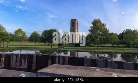Der historische Joseph Dill Baker Carillon Steinturm spiegelt sich im ruhigen Wasser des Carroll Creek hinter einer Stützmauer im Baker Park, Frederick, Stockfoto