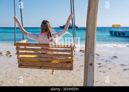 Frau, die sich auf einer Schaukel an einem tropischen Strand während eines friedlichen Sommerurlaubs in Sharm El She entspannt Stockfoto
