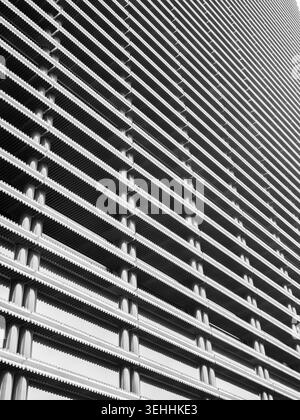Abstrakte moderne Gebäudefassade mit sich wiederholenden geometrischen Linien und architektonischen Mustern. Minimales Design, städtische Struktur, zeitgenössische Architektur, Stockfoto