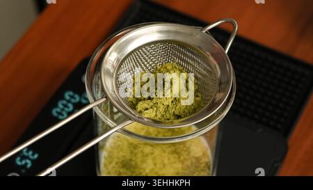 Grünes Matcha-Teepulver wird in eine Schüssel gesiebt, bereit für den traditionellen Matcha-Zubereitungsprozess. Stockfoto