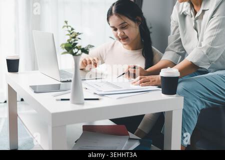 Zwei Frauen prüfen Finanzberichte und Diagramme zu Hause mit einem Laptop und Tablet und diskutieren dabei über Budgetplanung, Geschäftsanalyse und Online-Beratung Stockfoto