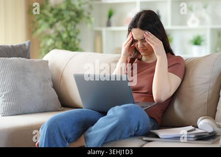 Junge Studentin mit Migräne, die zu Hause auf einer Couch sitzt Stockfoto