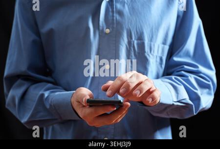Hände einer Person, die ein Smartphone hält, den Bildschirm berührt und scrollt, um eine digitale Verbindung herzustellen Stockfoto
