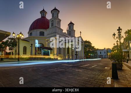 Blick auf die Blenduk-Kirche mit ihrer berühmten roten Kuppel und weißen Türmen in der Abenddämmerung mit Lichtspuren auf der kopfsteingepflasterten Straße, Semarang Utara, Zentral-Java, in Stockfoto