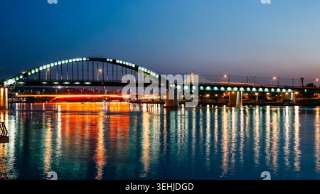 Blick auf die alte Save Brücke beleuchtet mit grünen Lichtern über die Save in der Abenddämmerung mit Reflexionen im Wasser Belgrad, Stadt Belgrad, Serbien Stockfoto