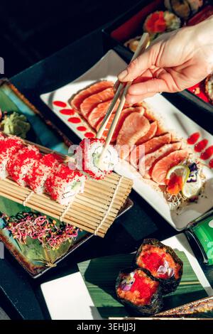 Leute in einer Sushi-Bar essen Sushi mit Essstäbchen. Blitz, Filmeffekt, Körnung Stockfoto