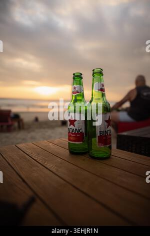 Zwei kalte Bintang-Biere auf einem Holztisch bei Sonnenuntergang an einem tropischen Strand in Bali, Indonesien. Stockfoto