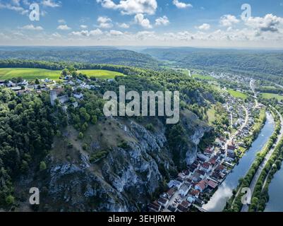 Blick aus der Vogelperspektive auf historische Burgruinen auf einem felsigen Hügel mit Blick auf ein Flusstal und ein traditionelles Dorf in Deutschland. Stockfoto