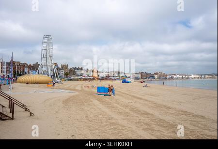Menschen am Sandstrand an einem heißen, sonnigen Frühlingstag im Mai in der Küstenstadt Weymouth an der englischen Südküste. Stockfoto