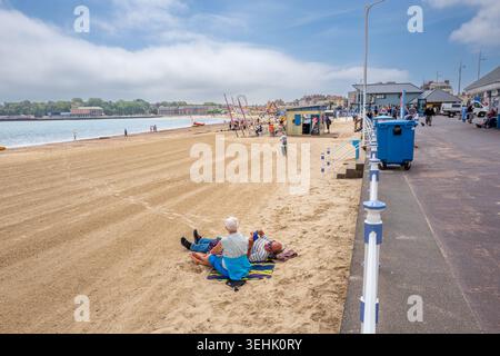 Menschen am Sandstrand an einem heißen, sonnigen Frühlingstag im Mai in der Küstenstadt Weymouth an der englischen Südküste. Stockfoto