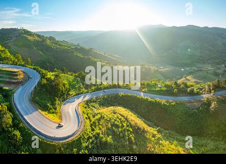 Aus der Vogelperspektive der berühmten Number Nine Sky Road, die sich während der goldenen Stunde durch die grünen Berge von Loei, Thailand, schlängelt. Gekrümmte Bergstraße in Loei Stockfoto
