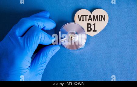 Vitamin B1-Symbol. Concept Words Vitamin B1 auf wunderschönem hölzernen Herzen. Arzthand in blauem Medizinhandschuh. Stethoskop. Wunderschöner blauer Hintergrund. Ich Stockfoto