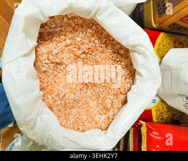 Avsallar, Türkei - 27. September 2025: Nahaufnahme eines weißen Sacks gefüllt mit rosafarbenem Himalaya-Salz, der auf einem Küchenregal unter verschiedenen Lebensmitteln platziert wird Stockfoto