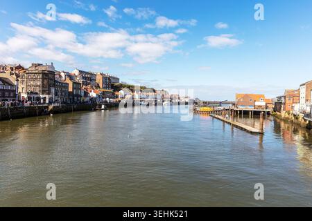 hafenszene in Whitby, North Yorkshire, zeigt Boote, die neben hölzernen Piers liegen, und ruhiges reflektierendes Wasser. Traditionelle Häuser und Geschäfte Stockfoto