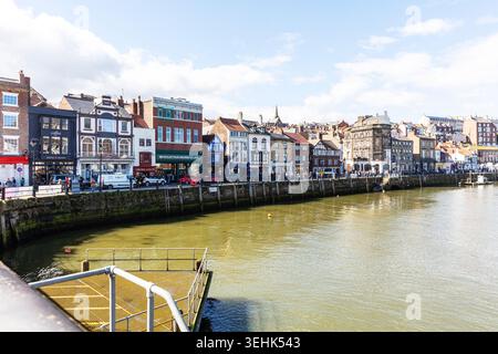 Eine Küstenszene in Whitby, North Yorkshire, zeigt eine Reihe historischer Gebäude entlang des Hafens. Die Mischung aus Ziegelsteinen und Putzfassaden, Geschäft Stockfoto