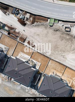 Blick aus der Vogelperspektive auf moderne Wohnhäuser im Bau mit einer Person, die auf dem unbefestigten Boden in der Nähe einer asphaltierten Straße in Avcilar, Istanbul, Türkei läuft. Stockfoto