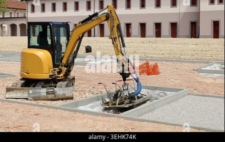 Minibagger mit Sonderausrüstung bei Parkplatzbauarbeiten. Stockfoto