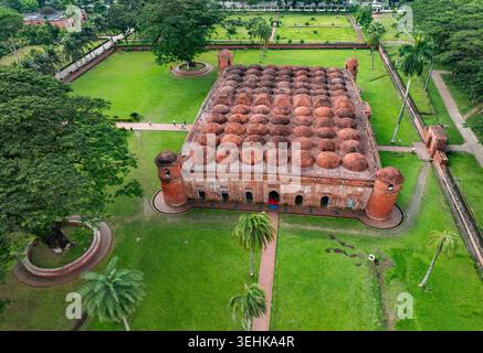 Blick aus der Vogelperspektive auf die Sixty Dome Moschee mit zahlreichen Terrakotta-Kuppeln und üppigen grünen Gärten, auf denen Menschen auf den Pfaden in Bagerhat, Khulna D, spazieren gehen Stockfoto