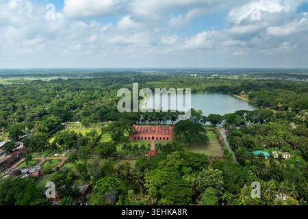 Blick aus der Vogelperspektive auf die historische Sixty Dome Moschee, umgeben von üppigen grünen Bäumen und einem großen Teich unter einem bewölkten Himmel in Bagerhat, Khulna Division, Banglad Stockfoto