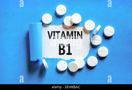 Vitamin B1-Symbol. Konzeptworte Vitamin B1 auf wunderschönem Weißbuch. Weiße Tabletten. Wunderschöner blauer Hintergrund. Medizinischer gesunder Lebensstil Vitami Stockfoto