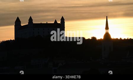 Silhouette der Burg Bratislava und der Kathedrale St. Martin bei goldenem Sonnenuntergang über der historischen Skyline der Stadt im Breitbildformat Stockfoto