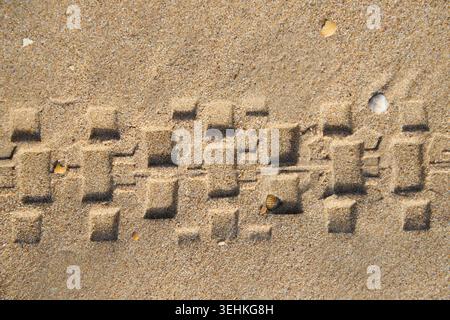 Reifenfußabdruck am Sandstrand Stockfoto