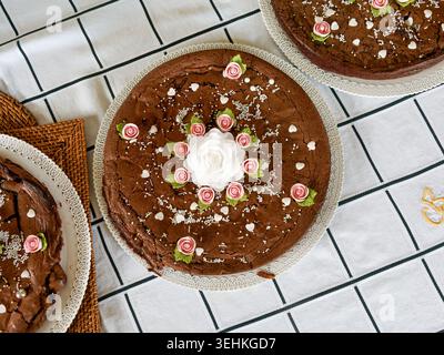 Blick von oben auf Schokoladenkuchen, dekoriert mit Glasur und Zuckerblumen auf einem Tisch. Stockfoto