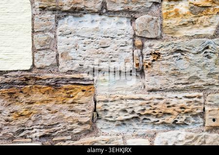 Verwitterte Steinblöcke an der Seite eines Gebäudes. Stockfoto