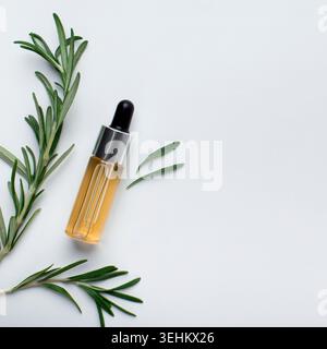 Ätherisches Rosmarinöl in einer kleinen Flasche und frischer Rosmarin Stockfoto