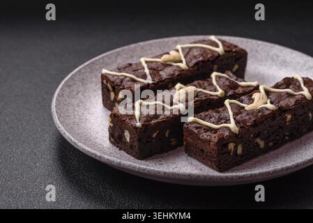 Essen, köstliche süße Brownies mit Schokolade und Nüssen auf dunklem Betonhintergrund Stockfoto