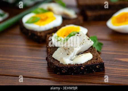 Nahaufnahme von Heringsbrot auf dunklem Roggenbrot. Stockfoto