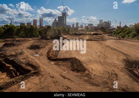 Ein großes freigelegtes Baugelände im Irk Valley mit der Skyline des Stadtzentrums von Manchester und Baukränen dahinter. Stockfoto