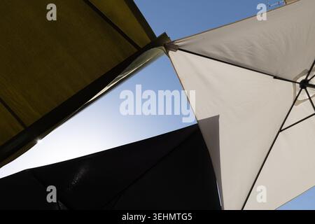 Abstrakte Sicht auf sich überschneidende Marktschirme vor blauem Himmel. Stockfoto
