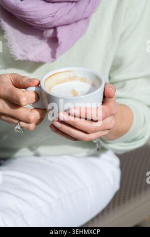 Nahaufnahme einer Frau, die einen warmen Cappuccino hält, während sie sich im Urlaub in Lecce, Apulien, entspannt und das Leben in Italien genießt Stockfoto