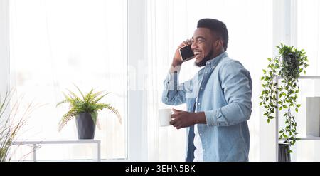 Junge fröhliche Geschäftsmann am Telefon sprechen und halten Kaffee Tasse Stockfoto