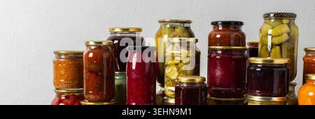 Canning ist eine häufige Aktivität in der Küche, da die Theke mit Gemüse und Obst gefüllte Gläser säumen. Diese Praxis hilft dabei, Lebensmittel für den Gewinn zu bewahren Stockfoto