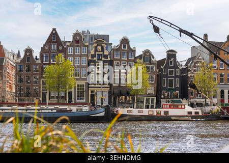 An einem sonnigen Tag in der Stadt erkunden die Besucher die historischen Kanäle Amsterdams voller einzigartiger Häuser und Boote. Stockfoto