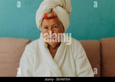 Seniorin mit Haaren, die nach dem Duschen in ein Handtuch gewickelt sind. Stockfoto