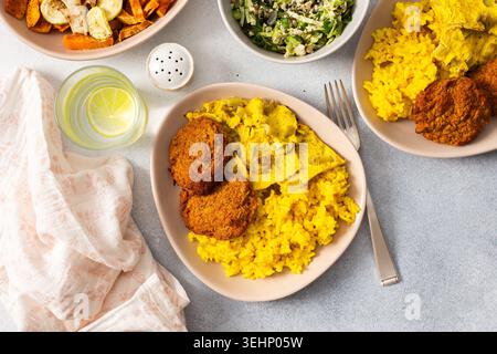 Ein farbenfrohes Aufstrich mit Reis mit Rhabarber-Spiegeleiern, gebackener Süßkartoffel und sautiertem Blumenkohl und Zucchini. Stockfoto