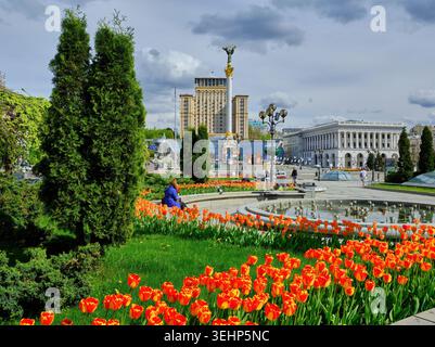Ein lebhaftes Bett aus roten Tulpen in voller Blüte vor dem Unabhängigkeitsdenkmal und dem Hotel Ukraine auf dem Maidan Nezalezhnosti (Unabhängigkeitsplatz) in Kyi Stockfoto